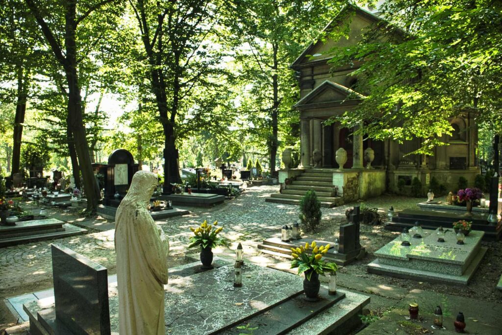 Eine schattige Allee auf dem Friedhof an der Francuska-Straße führt zu einer kleinen klassizistischen Kapelle – stille Grabstätten mit frischen Blumen zeugen von der gepflegten Erinnerungskultur.